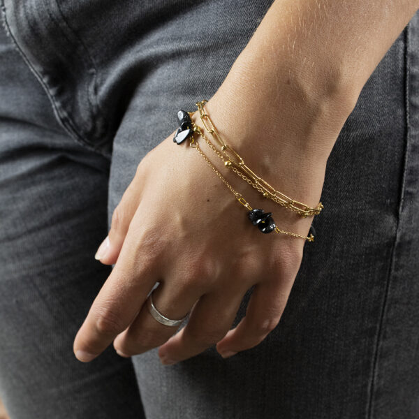 Bracelet en chaines mailles trombones et forçats en acier inoxydable avec fermoir bouée et perles d'agate noire, porté sur un poignet