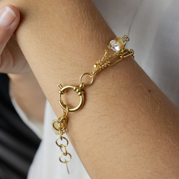 Bracelet en chaines mailles trombones et forçats en acier inoxydable avec fermoir bouée et perles de citrine, porté sur un poignet avec gros plan sur le fermoir