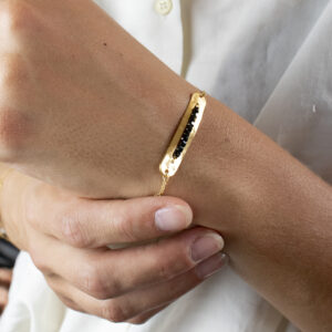 Bracelet avec un connecteur de forme rectangulaire arrondie, contenant des perles de spinelle, porté sur un poignet
