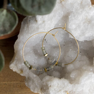 Boucles d'oreilles créoles en perles de labradorite posée sur une géode