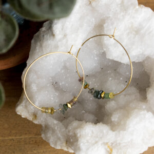 Boucles d'oreilles créoles en perles d'agate mousse et de fluorite posée sur une géode