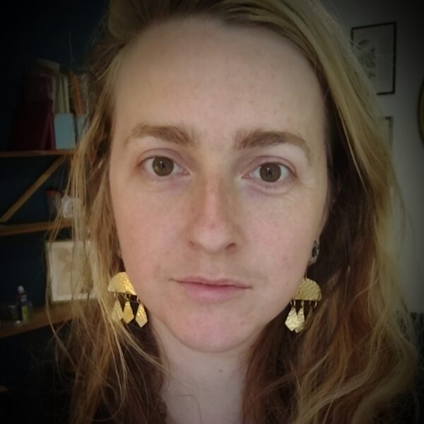 Visage avec, aux oreilles, des boucles d'oreilles avec arc de cercle et pampilles en laiton martelé